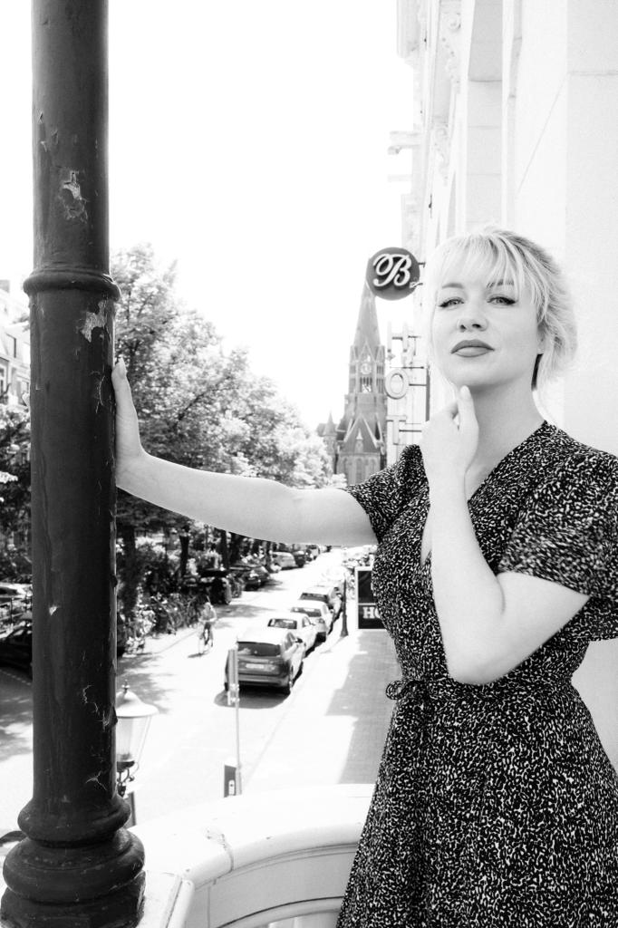 Zwart-witportret van Bianca Frölich op een balkon, met de Vondelkerk op de achtergrond